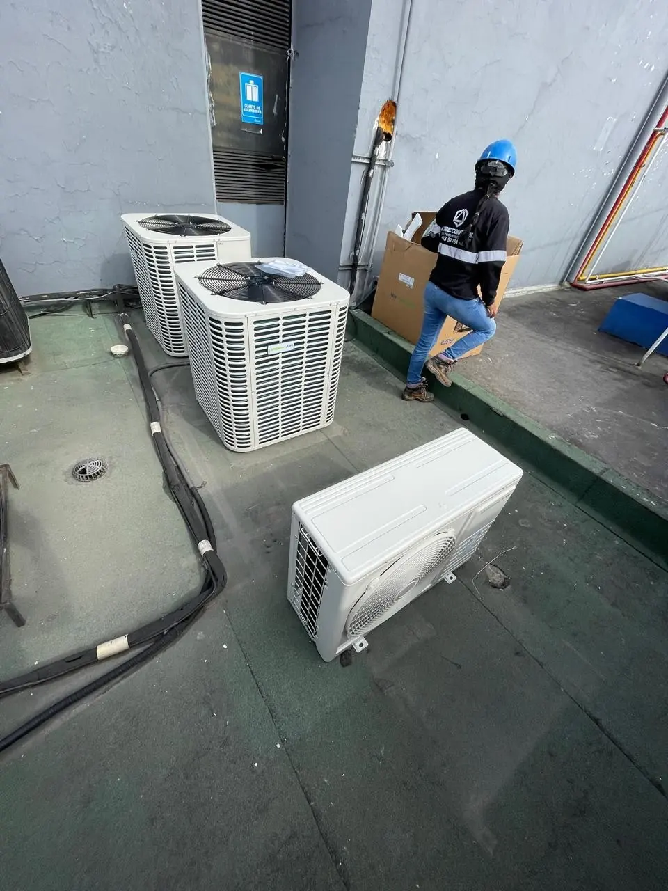 Unidades condensadoras de aire acondicionado en una terraza y un técnico de Airecontrol