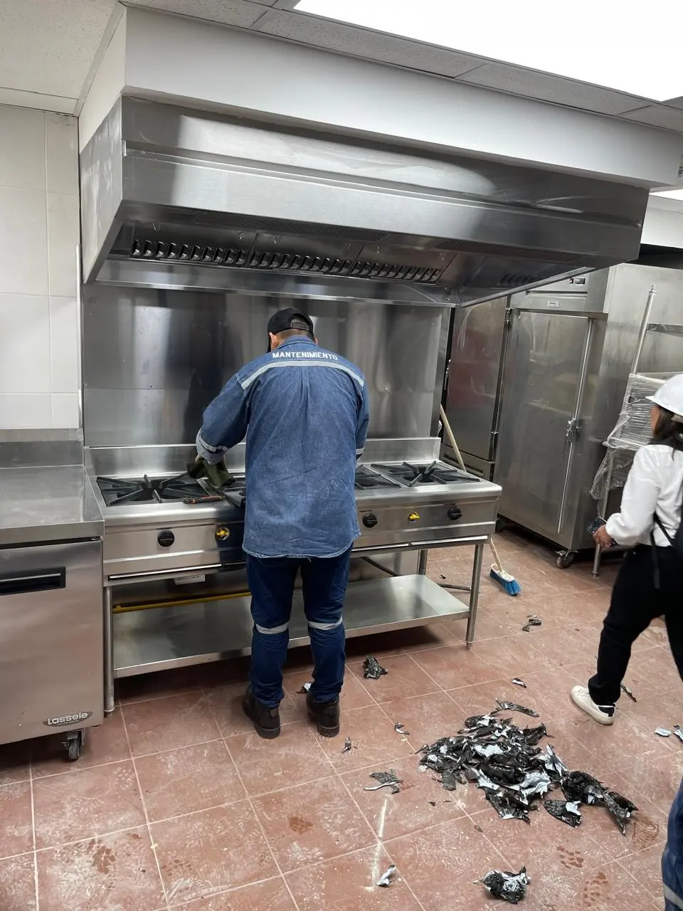 Cocina industrial con campana de acero inoxidable y un técnico frente a la cocina