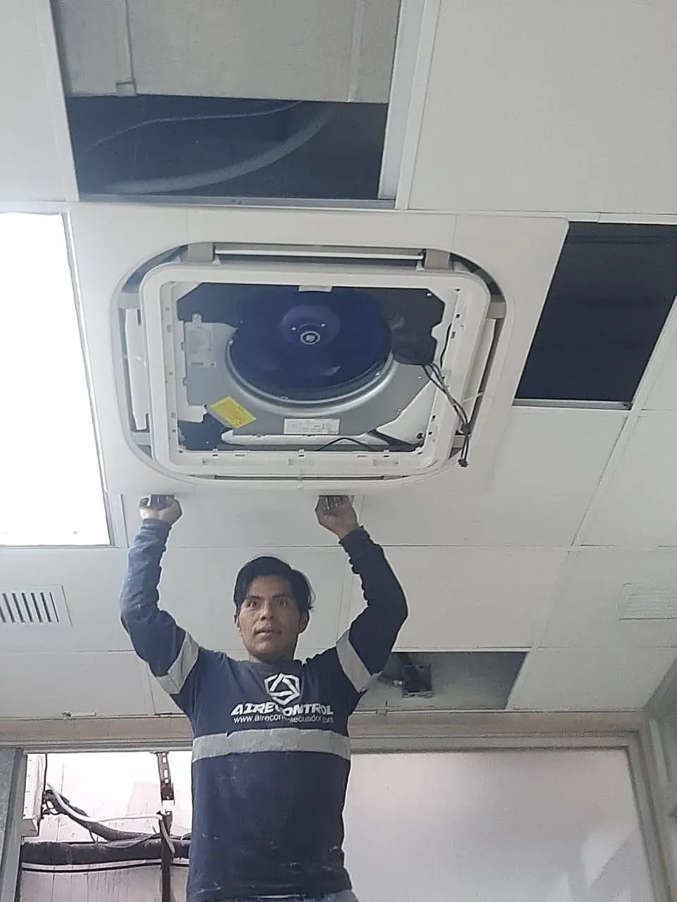 Técnico de Airecontrol trabaja en un equipo de aire acondicionado tipo cassette del cielo raso