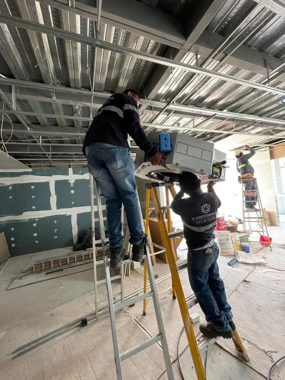 Dos técnicos de Airecontrol trabajan en un equipo del cielo desde escaleras