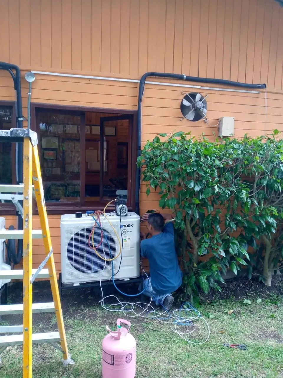 Técnico revisa una unidad exterior de aire acondicionado