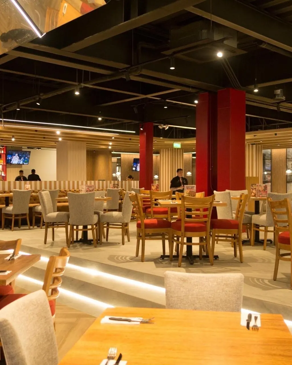 Salón de un restaurante con columnas rojas y la climatización a la vista en el cielo negro